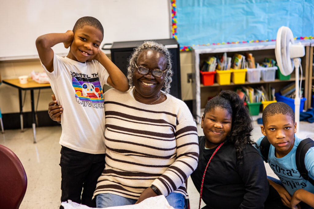 At a Philly Families Read Together event, a grandmother smiles between 3 grandchildren.