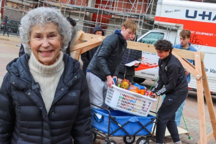 Philly Families Connect Coordinator poses in front of St. Joseph's Prep students at a Thanksgiving Giveaway
